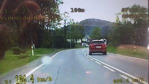 zdjęcie z videorejestratora, na którym widoczny jest samochód osobowy jadący po jezdni oraz informacja cyfrowa o prędkości jadącego samochodu 106 km