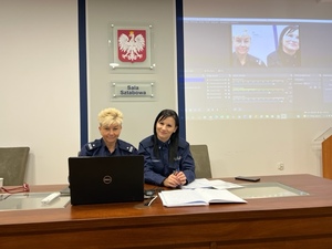 dwie policjantki siedzą przed komputerem w sali sztabowej komendy policji , na stole leża karki papieru