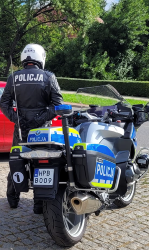policjant stoi przy motocyklu na poboczu drogi