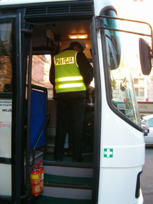 policjant stoi w autobusie i prowadzi kontrole
