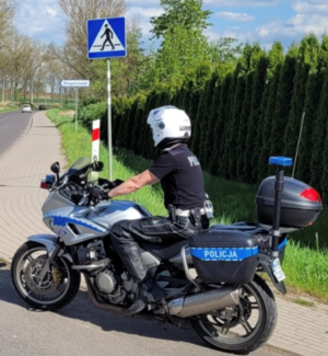 policjant siedzi na motocyklu służbowym w tle widać drogę