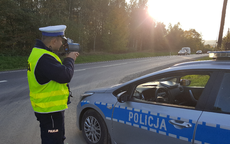 policjant stoi przy radiowozie na drodze