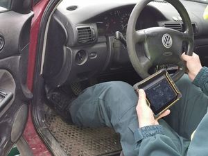 funkcjonariusz z tabletem w ręku siedzi za kierownicą kontrolowanego pojazdu