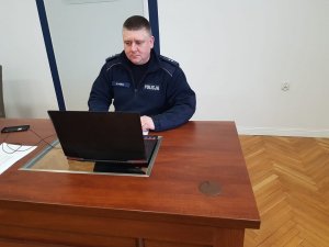 policjant siedzi przy komputerze w sali sztabowej kłodzkiej policji i prowadzi zajecia online.