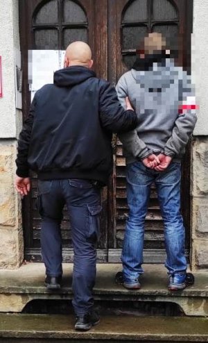 policjant prowadzi mężczyne zatrzymanego