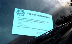 ulotka za szybą samochodu, na niej treść prewencyjna  z logo policji-gwiazdą policyjną