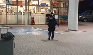 policjantka idzie w kierunku sklepu na stacji paliw