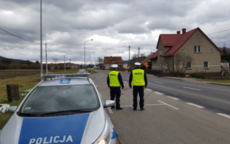 Patrol policj stoi na drodze , widać zaparkowany radiowoz