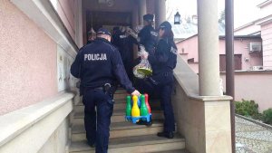 policjanci wchodzą do budynku i niosą paczki