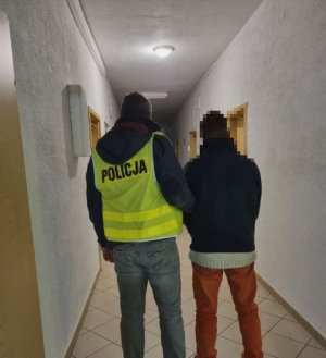 policjant prowadzi zatrzymanego meżcyzne