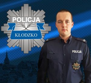 zdjęcie policjanta  w mundurze, po lewej stronie logo policji kłodzko-gwiazda policyjna