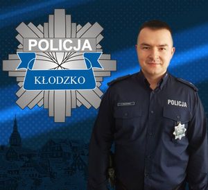 zdjęcie policjanta w mundurze, na górnej części znajduje się logo policji powiatu kłodzkiego