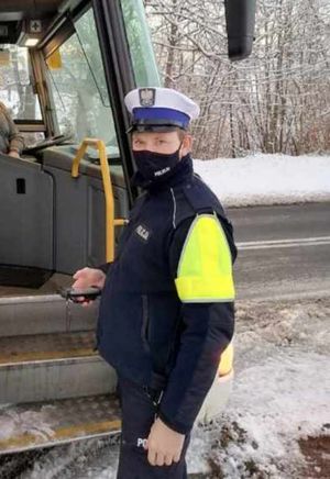 policjant stoi przy autokarze , na ziemi leży śnieg