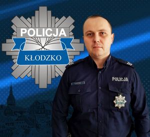 zdjęcie policjanta , a w górnej części umieszczone logo policji powiatu kłodzkiego -gwiazda policyjn