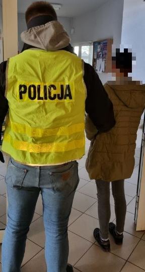 policjant prowadzi zatrzymaną kobietę