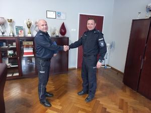 W gabinecie Komendant powiatowy Policji wręcza policjantowi akt powołania na stanowisko