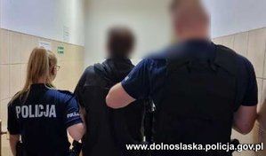 policjantka i policjant  prowadzą zatrzymanego mężczyznę