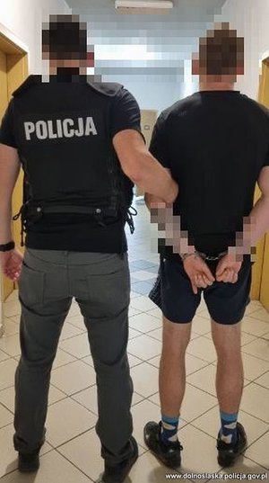 policjant operacyjny  prowadzi zatrzymanego mężczyznę