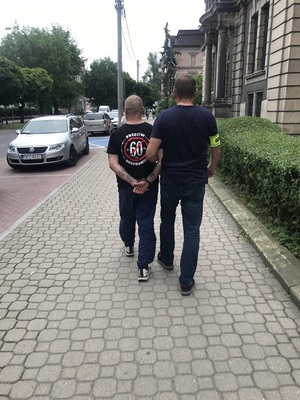 Policjant doprowadza zatrzymanego mężczyznę do sądu.