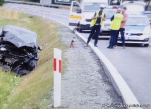 policjanci wykonują czynności służbowe na miejscu wypadku drogowego, stoi uszkodzone auto i widać ulice oraz pobocze