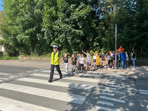 policjantka prowadzi dzieci przez przejcie