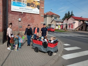 dzieci sierdzą w wózku , obok stoi policjant i kobiety