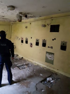 policjant stoi w pomieszczeniu pustostanu,ściany y brudne i popisane