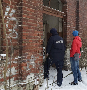 mężczyzna stoi z policjantem przy wejściu do pustostanu