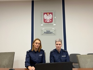 dwie policjantki siedzą obok siebie przy komputerze w sali sztabowej, na ścianie godło państwowe oraz napis sala sztabowa