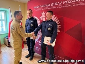 komendant straży Pożarnej składa gratulacje dwóm policjantom