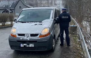 policjant prowadzi kontrole drogowa, widać samochód typu bus