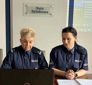 dwie policjantki w mundurach siedzą przy komputerze w sali sztabowej, na ścianie tabliczka z napisem sala sztabowa