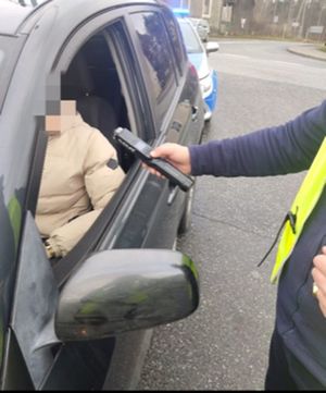 policjant prowadzi kontrole stanu trzeźwości kierującego samochodem