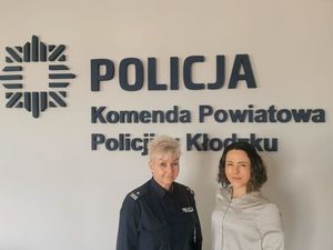 policjantka w mundurze i kobieta ubrana w szarą bluzkę stoją na tle napisu Policja Komenda Powiatowa Policji w Kłodzku