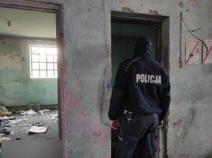 policjant stoi w pustostanie, widać brudne ściany i śmieci na podłodze