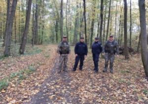 policjanci i strażnicy leśni stoją obok siebie w lesie