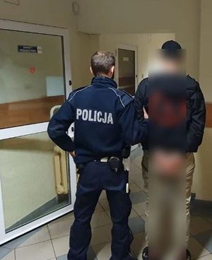 policjant prowadzi zatrzymanego meżczyne