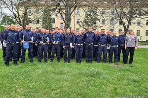 grupa policjantów stoi obok siebie kilku z nich trzyma w rękach puchary