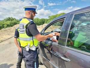 policjant stoi przy samochodzie osobowym