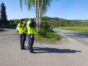 patrol policji stoi na poboczu drogi i mierzy prekosć jadącego pojazdu na drodze