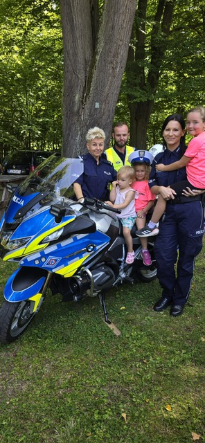 zdjęcie z festynu w plenerze, policjantki i policjant  z dziećmi przy motocykliu