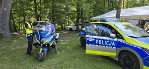 zdjęcie z festynu w plenerze, radiowóz i motocykl policyjny oraz policjanci i uczestnicy festynu