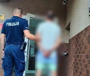 policjant prowadzi zatrzymanego do budynku komendy policji