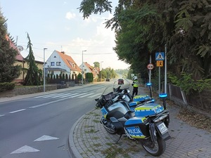 da motocykle policyjne zaparkowane e na poboczu drogi i policjanci stoją obok