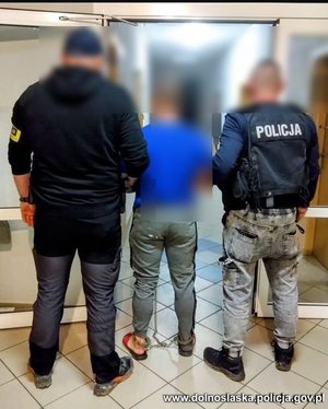 policjanci  prowadzą zatrzymanego mężczyznę