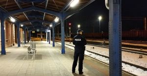 policjant stoi przy peronach, widać dookoła śnieg, zdjęcie zrobione w porze nocnej