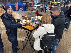 Policjantka w mundurze stoi przy stole z ciastem