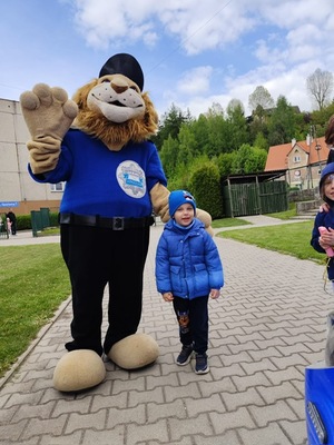 dziecko stoi z komisarzem lwem -maskotką