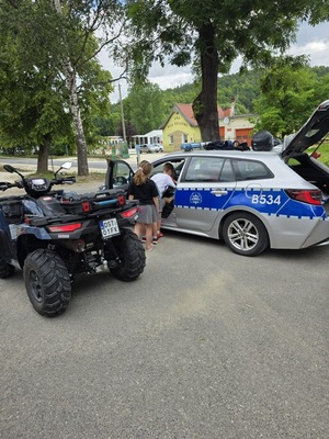 quad i policyjny radiowóz zaparkowany na placu , w pobliżu są dzieci