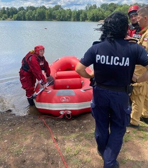 Policjantka i strażak stoją na brzegu przy łodzi